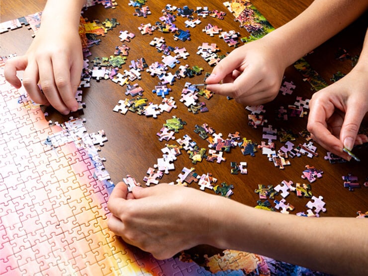 Hands solving a landscape jigsaw puzzle