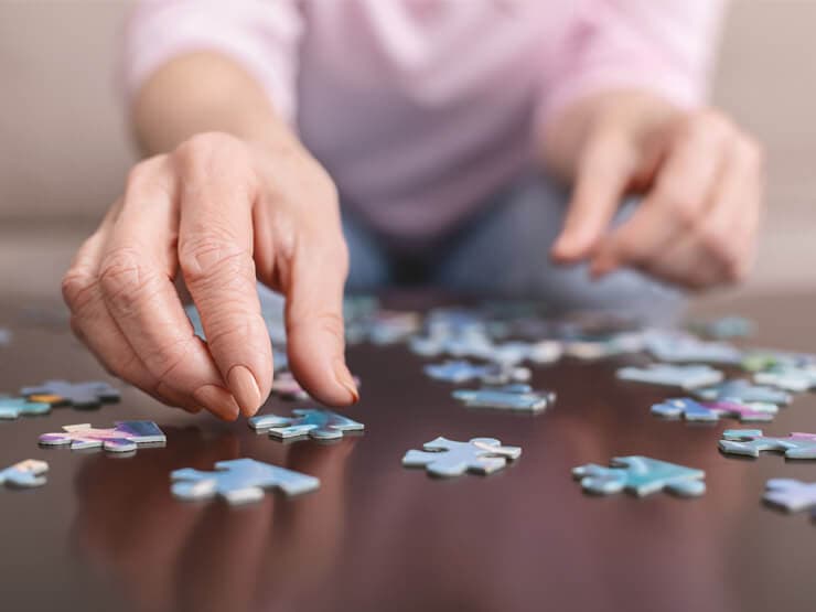 Hands of an elderly lady solving a jigsaw puzzle