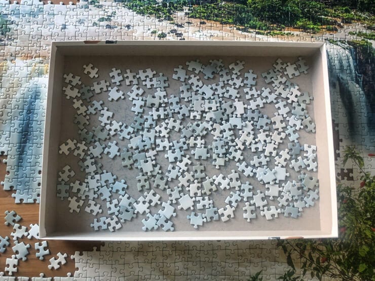 Puzzle pieces in a box on the background of a nearly finished puzzle