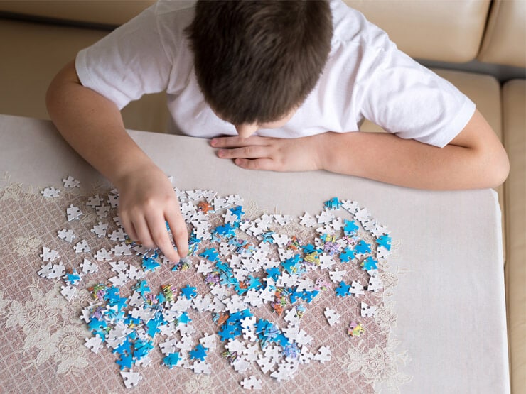 A teenage boy solving a jigsaw puzzle