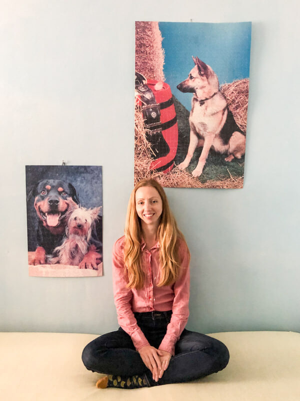 Posing in front of a wall with hung dog jigsaw puzzles
